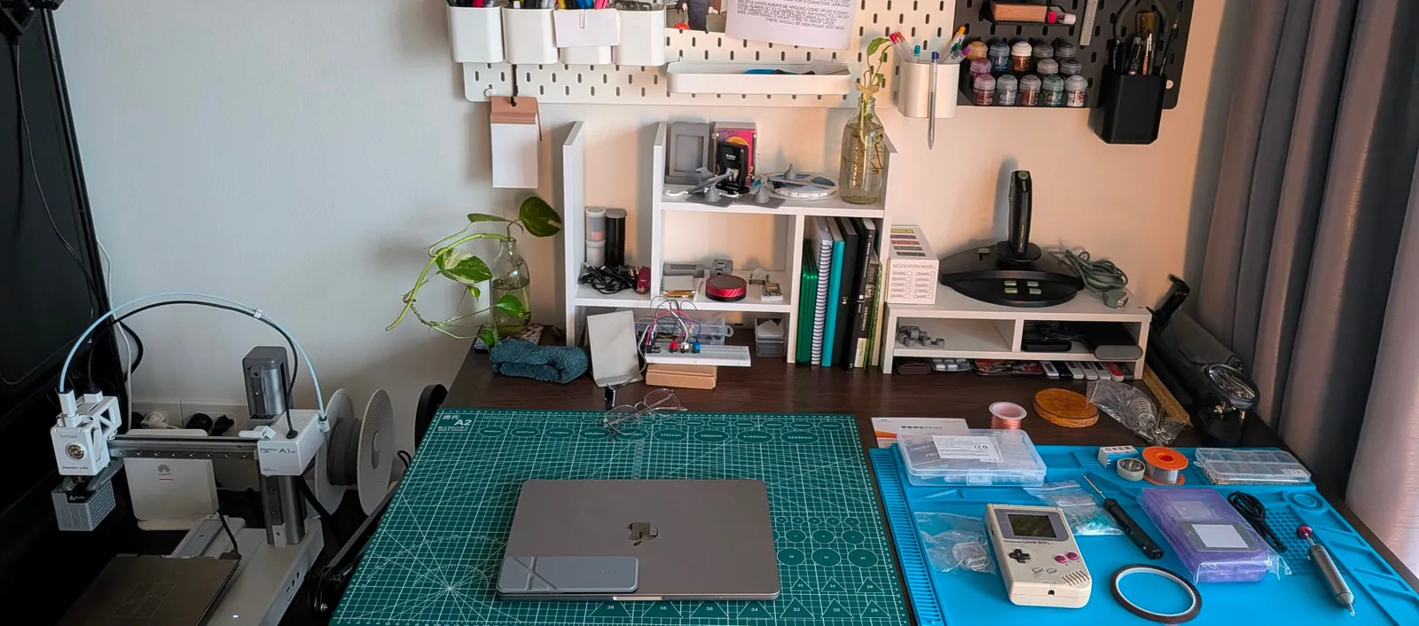 Trevor’s workbench with a 3D printer, cutting mat, electronics and handheld devices
