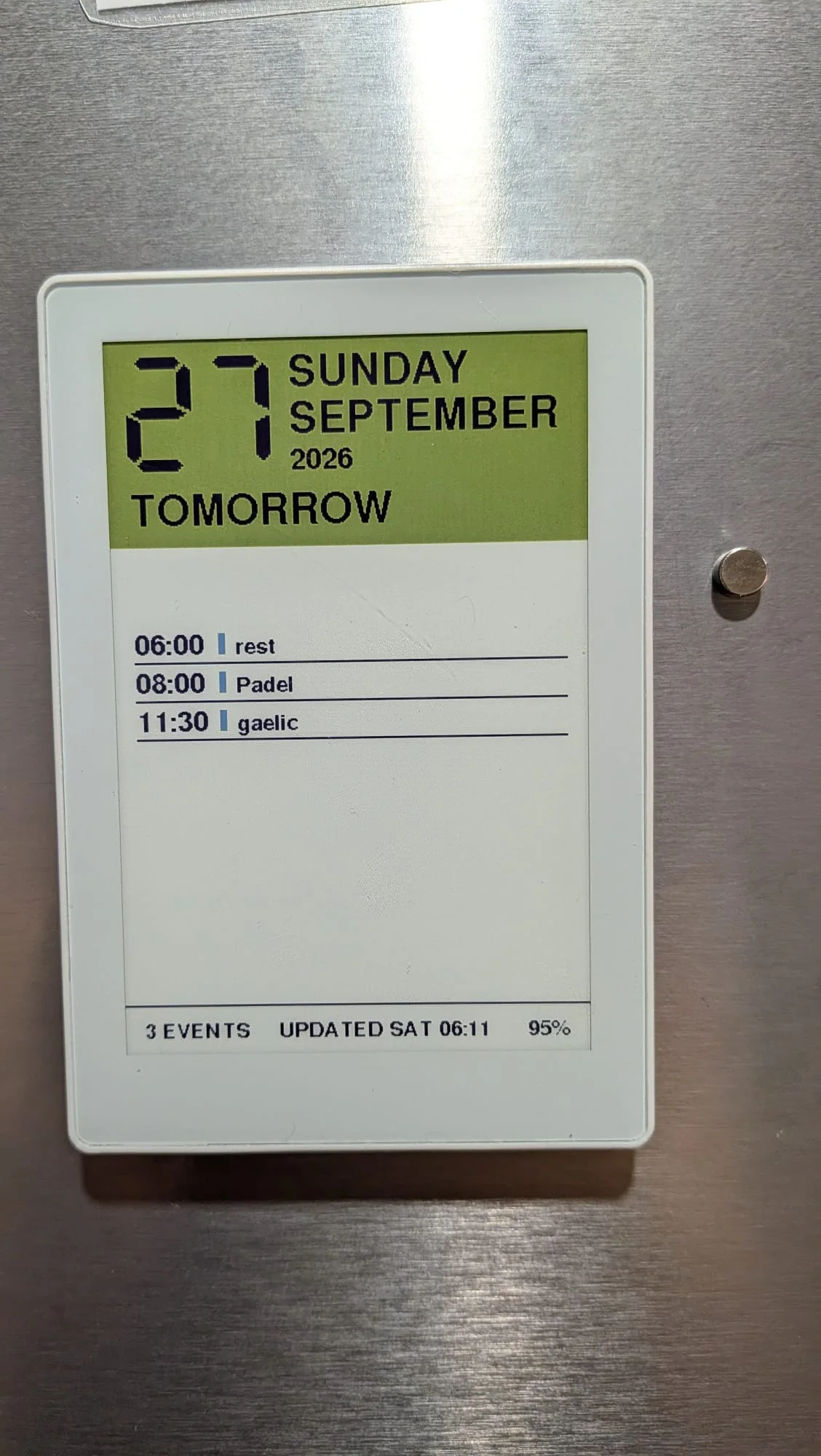 M5Stack PaperColor on a steel fridge door showing a green date band and three events