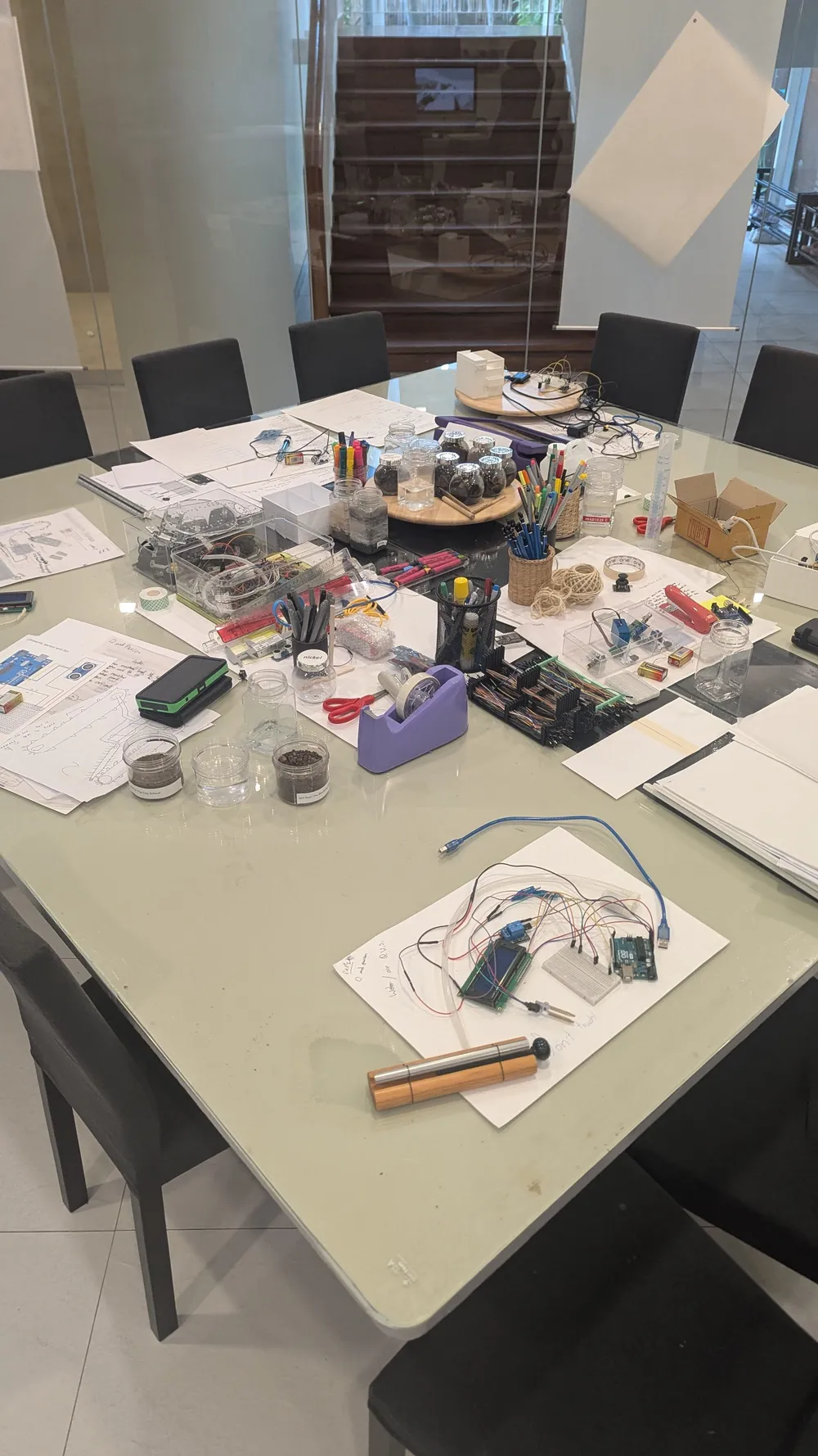An atelier table holding sketches, electronics and making materials